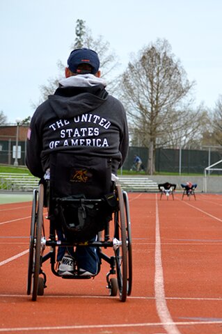 Adam Bleakney coaches members of the Illinois wheelchair track team.